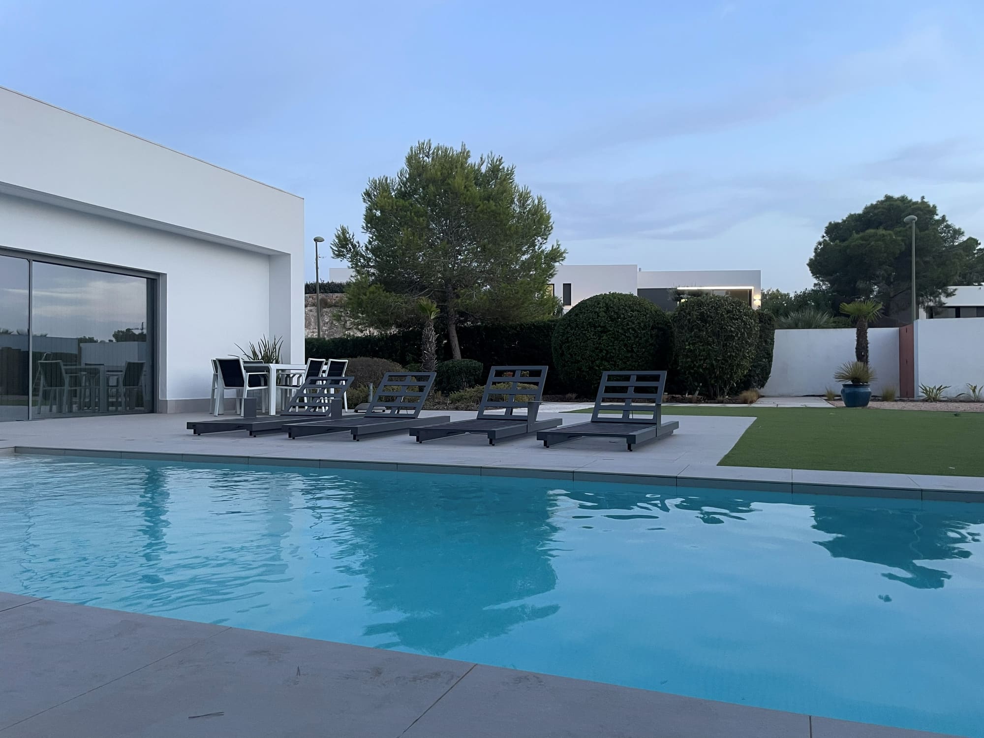 Modern white villa with pool, sun loungers and landscaped garden at dusk on the Costa Blanca